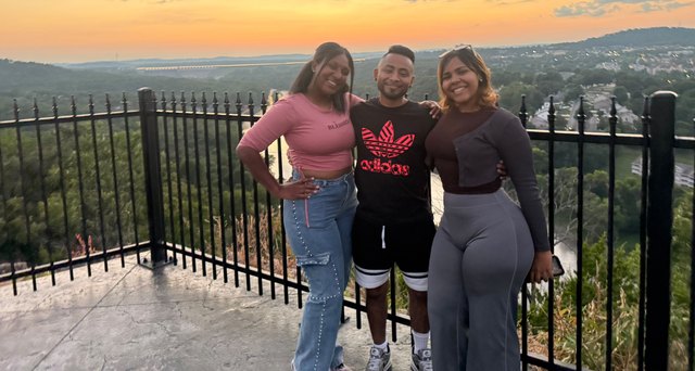 Three friends pose against a hillside landscape at sunset in Branson.