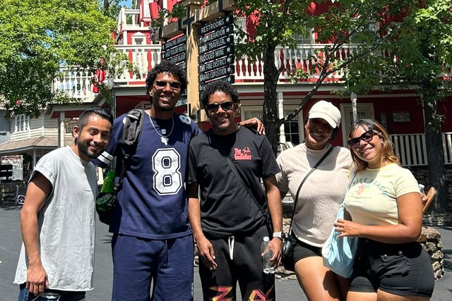 Five friends pose together among trees and buildings at an attraction in Branson.