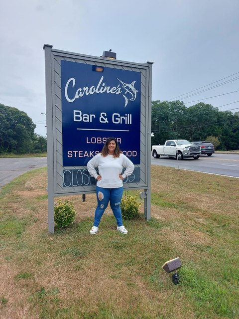 Joven frente al letrero de Caroline’s Bar & Grill.