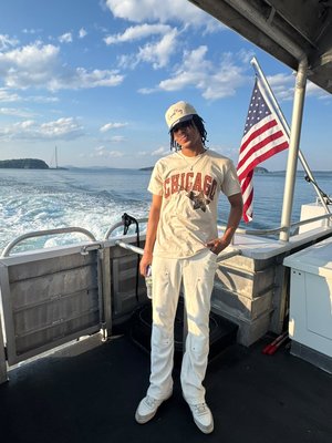Joven en la cubierta de un barco, junto a una bandera de Estados Unidos.